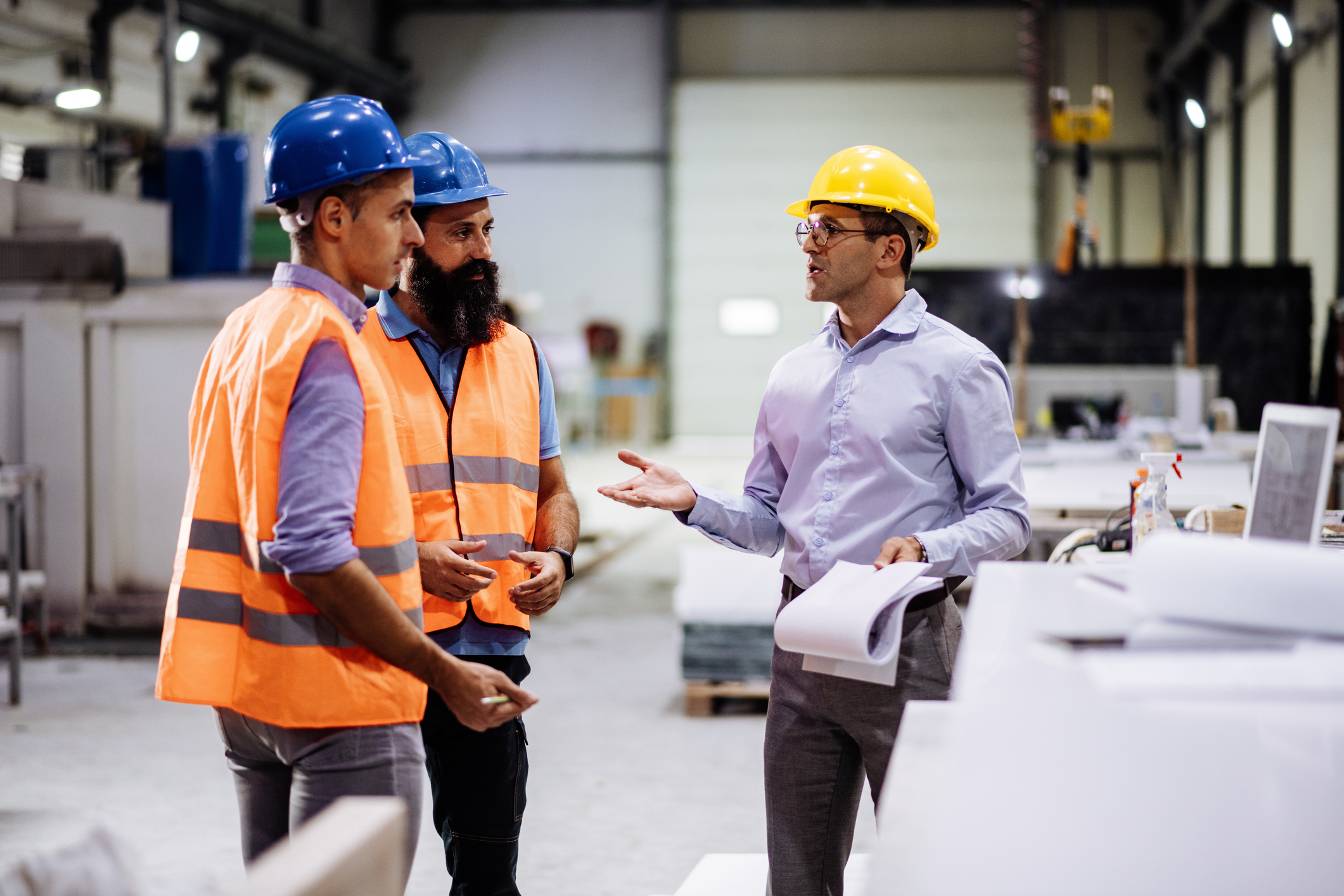 Engineers in factory hall, performing quality control. Workers compensation risk management.